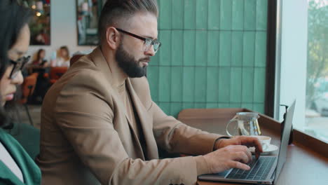 Businessman-Typing-on-Laptop-in-Cafe